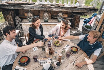 Zwei Päärchen stossen mit einem Glas Rotwein an.  | © Gabriel Perren