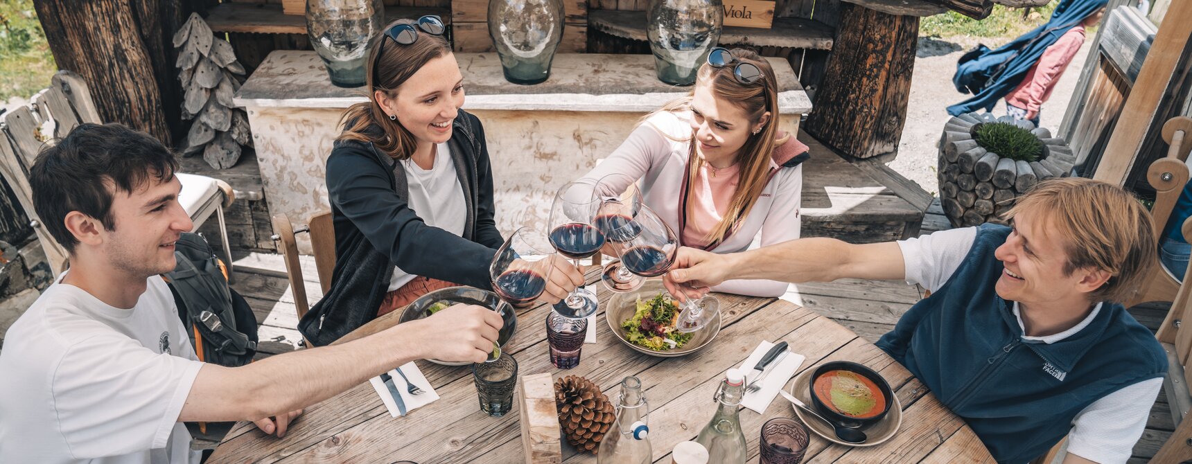 Zwei Päärchen stossen mit einem Glas Rotwein an.  | © Gabriel Perren