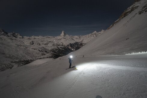 Skifahrer mit Stirnlampe auf dunkler Piste mit Matterhorn im Hintergrund | © Gabriel_Perren