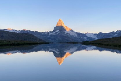 Klassischer Sonnenaufgang mit Spiegelung des Matterhorns mit leuchtendem Gipfel im klaren Stellisee | © Zermatt Bergbahnen