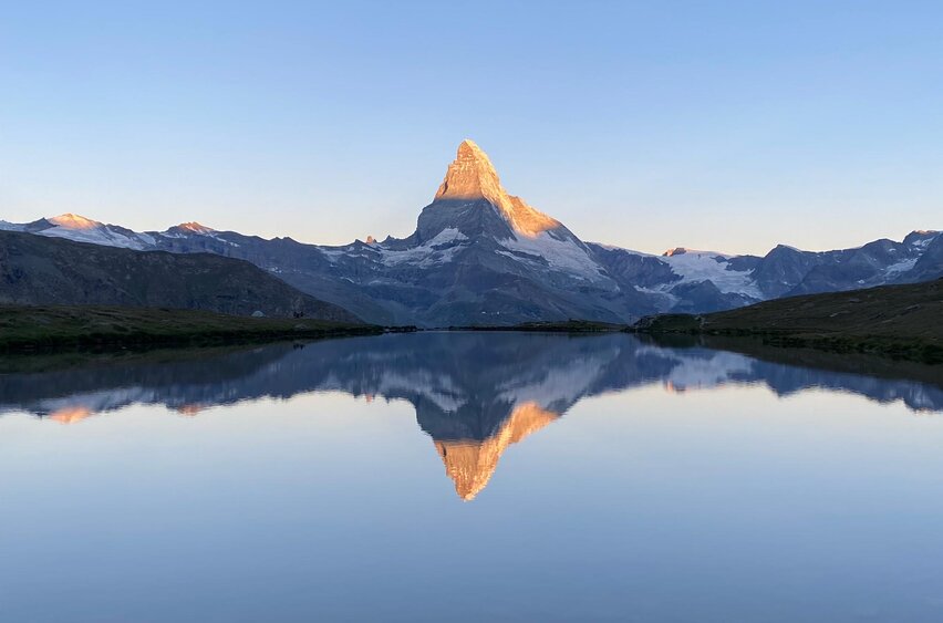 Klassischer Sonnenaufgang mit Spiegelung des Matterhorns mit leuchtendem Gipfel im klaren Stellisee | © Zermatt Bergbahnen