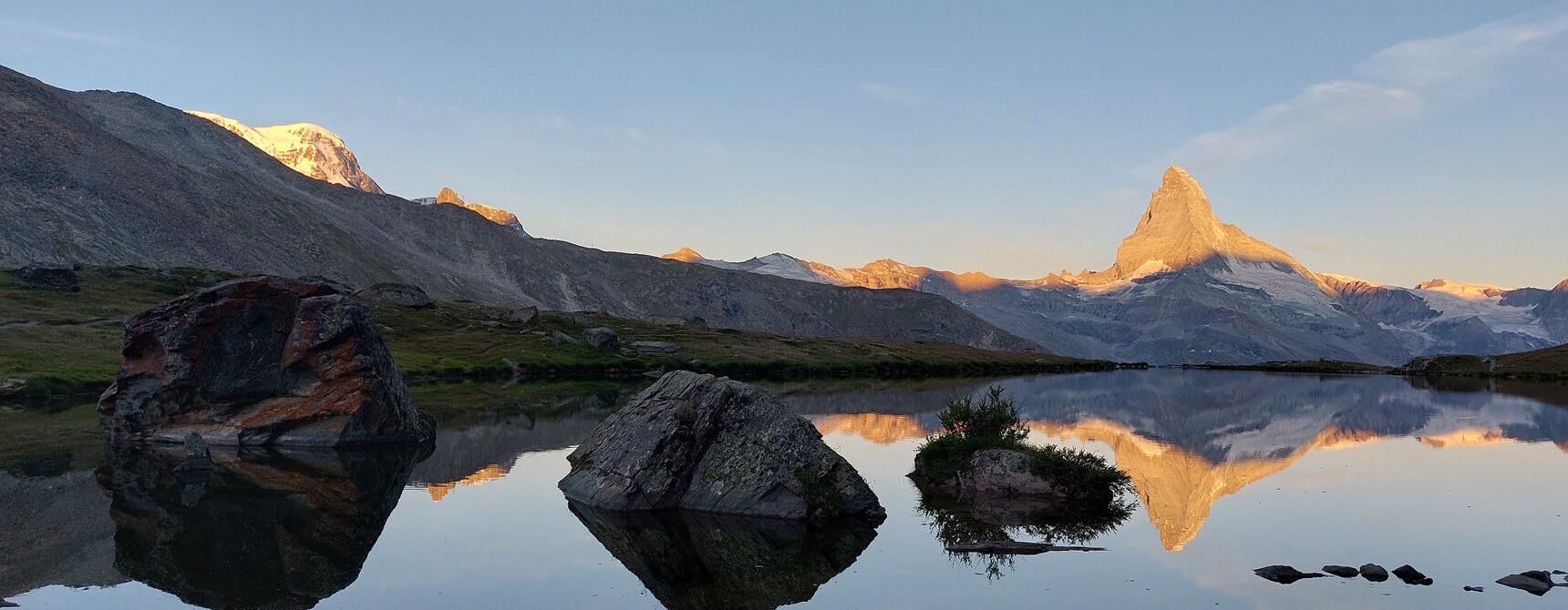 The Matterhorn is reflected in Lake Stelli. The peaks around the Matterhorn are equally illuminated by the first rays of sunshine | © Zermatt Bergbahnen