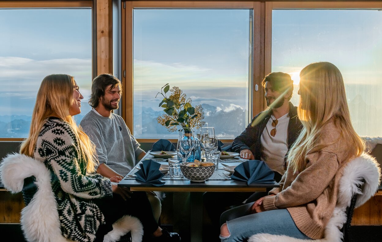 Zwei Pärchen sitzen bei Sonnenuntergang am Tisch des Glacier Paradise Restaurant | © basic home production