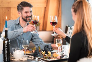 A couple toasts with a glass of wine at sunset dinner in Matterhorn Glacier Paradise. | © Basic Home Production