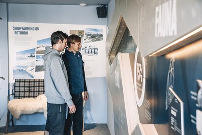 Two men look at the information boards in the Alpine Lounge on Blauherd.  | © Gabriel Perren
