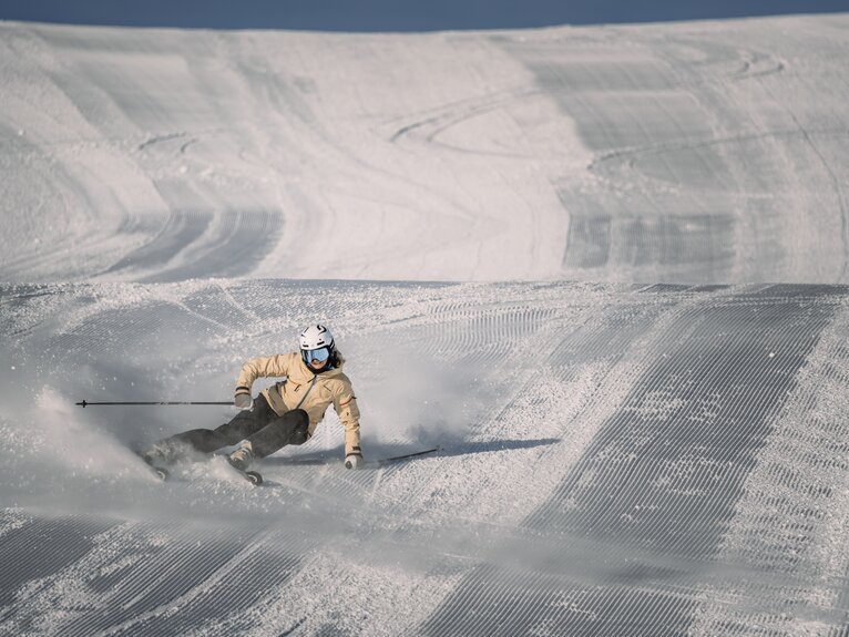 Skifahrerin macht eine Linkskurve auf frisch präparierten Pisten. | © Gabriel Perren