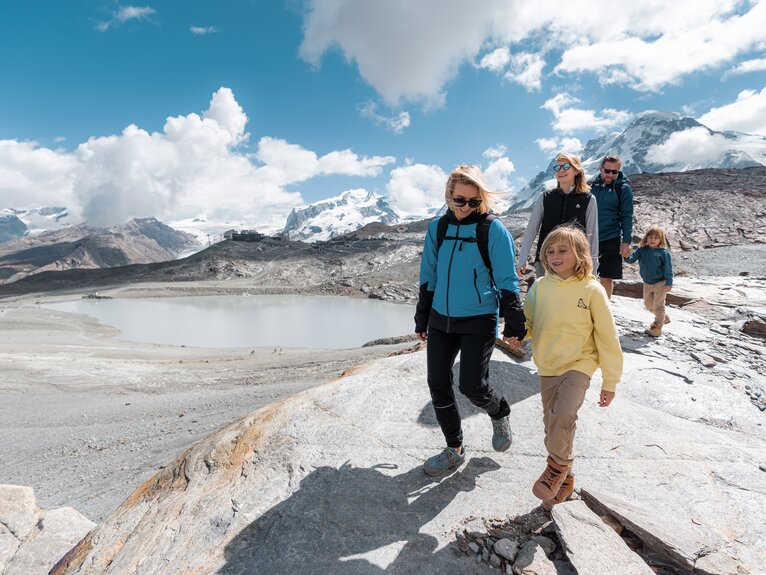 Family with three children hiking over rocks, the mountains of Zermatt in the background | © basic_home