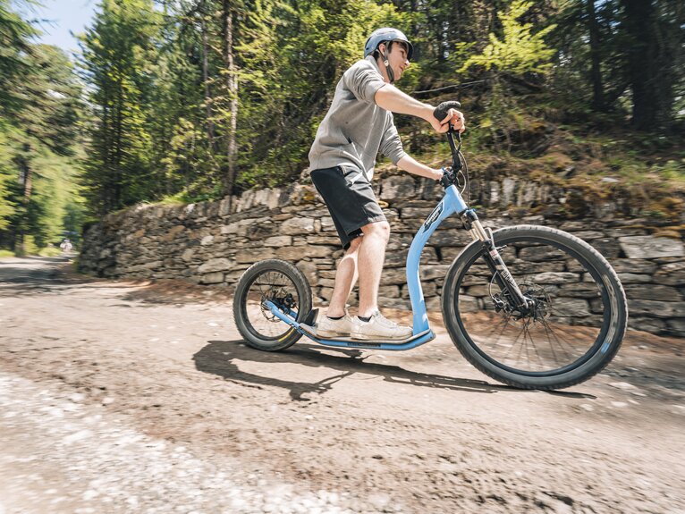 A man zips along the forest on a kickbike.  | © Gabriel Perren
