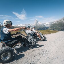 Un groupe est assis dans son mountaincarts, prêt à partir, par un temps idéal et avec une vue sur le Cervin.  | © Gabriel Perren